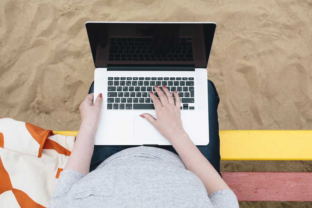 Person using laptop on the beach.